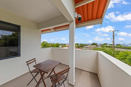 a balcony with a wooden chair and a window at Vista Papaya Suites in Westpunt