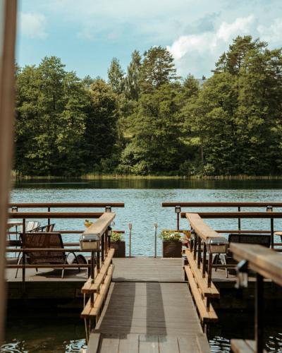a dock on a lake with benches on it at Akmenos Villas & Bungalow in Bražuolė