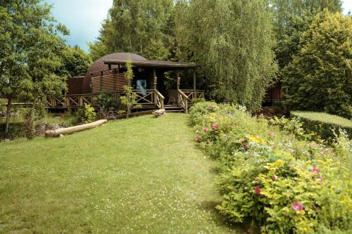 a garden with a gazebo and some flowers at Akmenos Villas & Bungalow in Bražuolė