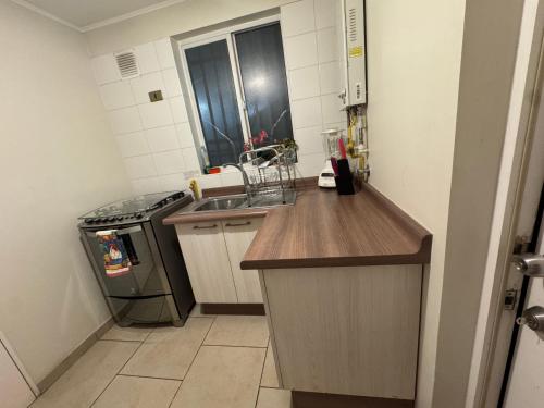 a small kitchen with a sink and a stove at Casa amplia tres dormitorios 5 camas y estacionamiento in Padre Las Casas