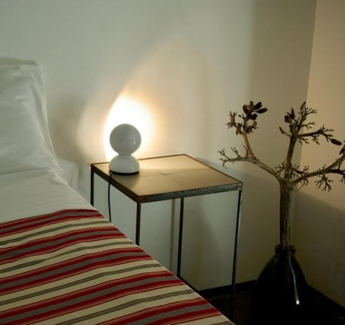 a table with a lamp on it next to a bed at Casa nel Sud-Est in Cava dʼAliga