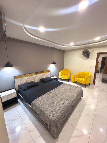 a bedroom with a bed and two yellow chairs at Luxury 1BHK Apartment in Rawalpindi