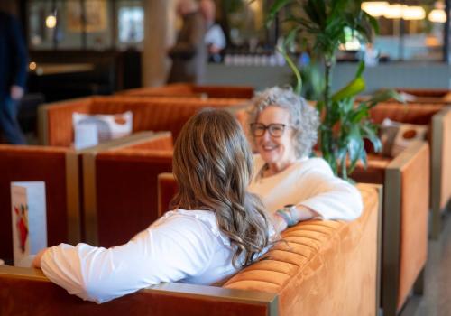 a woman sitting on a bench in a restaurant at voco The Club - Dublin Gateway by IHG in Naas