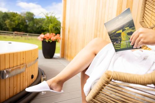 a woman sitting in a wicker chair reading a book at voco The Club - Dublin Gateway by IHG in Naas