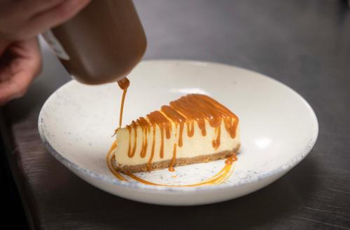 a piece of cake with caramel sauce on a white plate at voco The Club - Dublin Gateway by IHG in Naas