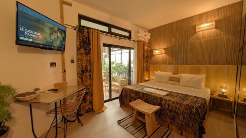 a bedroom with a bed and a television and a table at La Maison de Canelya in Cotonou