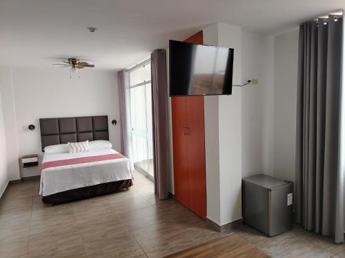 a bedroom with a bed and a flat screen tv at Casa Yuraq Hotel Boutique in Chincha Alta