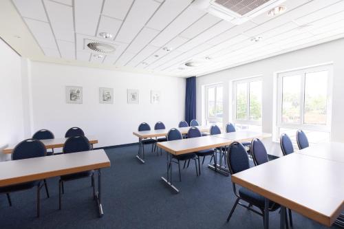 a classroom with tables and chairs in a room with windows at Garner Hotel Cottbus Süd by IHG in Cottbus
