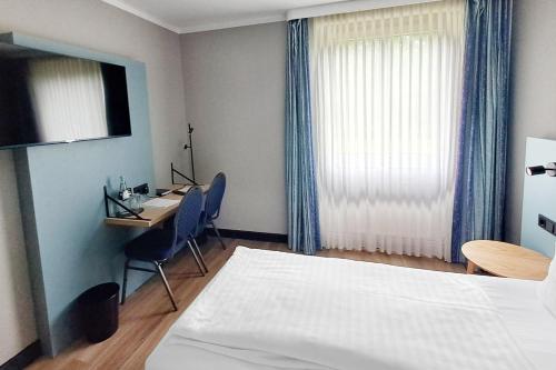 a hotel room with a bed and a desk with a computer at Garner Hotel Cottbus Süd by IHG in Cottbus