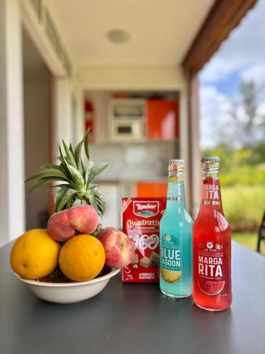 a bowl of fruit and two bottles of soda at La Gaëline - Wifi, Accès Plage 2 Min à Pieds in Grand-Bourg