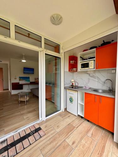 a kitchen with orange and white cabinets and a living room at La Gaëline - Wifi, Accès Plage 2 Min à Pieds in Grand-Bourg