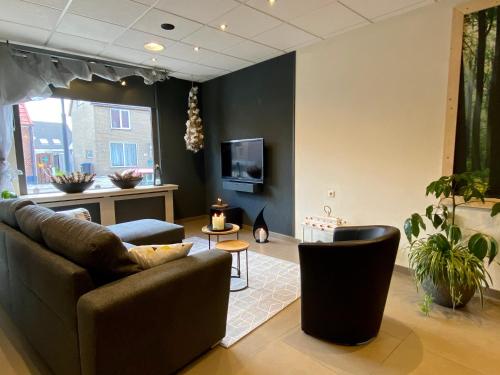 a living room with a couch and chairs and a tv at Kom tot rust in The Forest in Putte