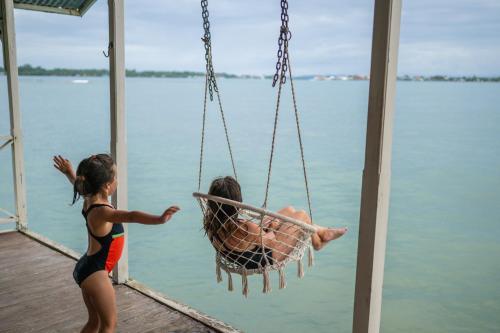 two children playing in a swing over the water at La Caribena Beach House- Bocas del Toro, Isla Colón, Panamá in Big Creek