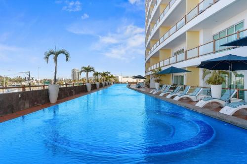a swimming pool at a hotel with chairs and umbrellas at Deck12 Casino and Resort by Monyxbnb in Puerto Vallarta