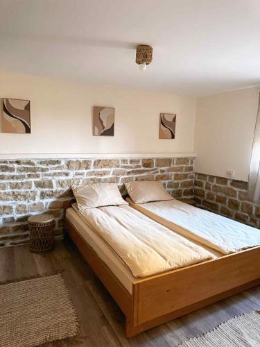 a bed in a room with a brick wall at Къща за гости "Хармония" - Луковит in Lukovit