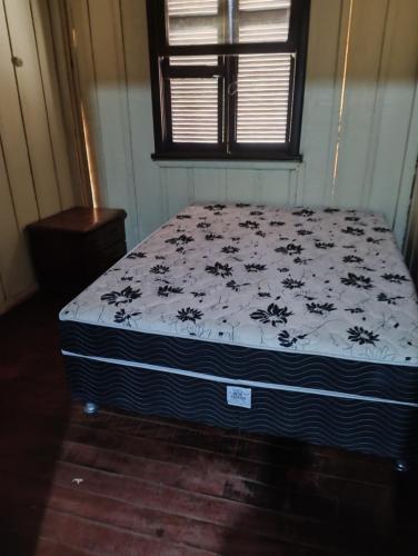 a bedroom with a bed with a black and white comforter at Casa de madeira in Matinhos