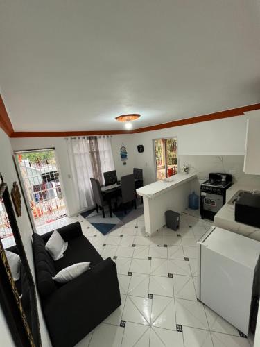 a living room with a black couch and a kitchen at Apart nuevo boca chica in Boca Chica