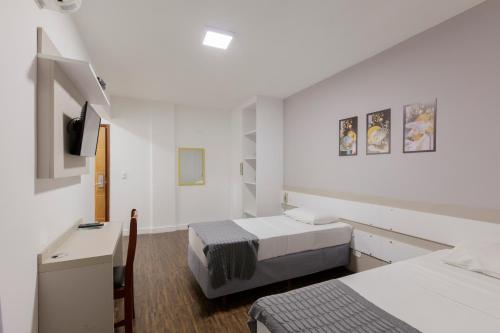 a bedroom with two beds and a desk and a tv at Cardim Plaza Hotel in Sao Paulo
