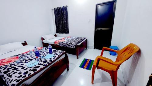 a room with two beds and a table and a chair at Nilam Guest House in Bodh Gaya