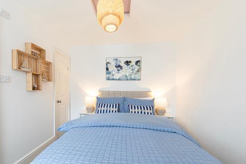 ein blaues Bett in einem weißen Schlafzimmer mit blauer Tagesdecke in der Unterkunft Sea Shore Apartment in Llandudno