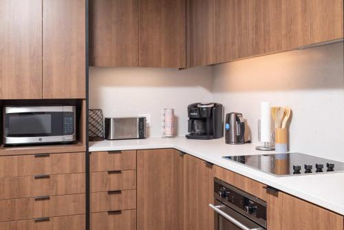 a kitchen with wooden cabinets and a microwave and appliances at North End TD Garden Condo Shared Pool & Rooftop in Boston