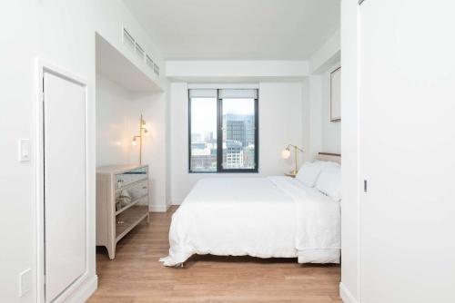 a white bedroom with a large bed and a window at North End TD Garden Condo Shared Pool & Rooftop in Boston