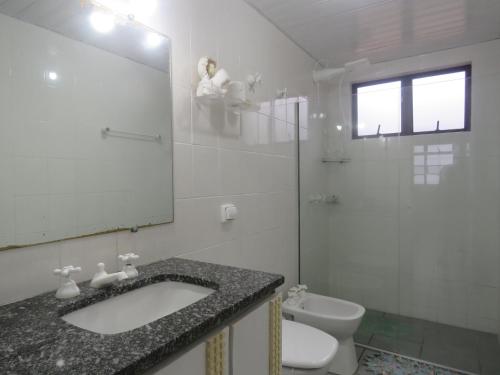 a bathroom with a sink and a toilet and a mirror at Ap Matinhos - Pé na areia e Vista para o Mar - Praia Brava - Caiobá in Matinhos