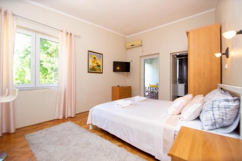 a bedroom with a large white bed and windows at ACIKA apartments in Rafailovici