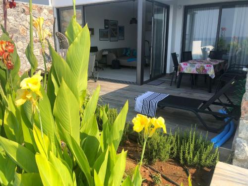 a patio with a table and some yellow flowers at Oceanfront Oasis with Private Pool Stunning Views in Kérynia