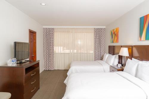 a hotel room with two beds and a flat screen tv at Hotel Los Andes in San Pedro Sula