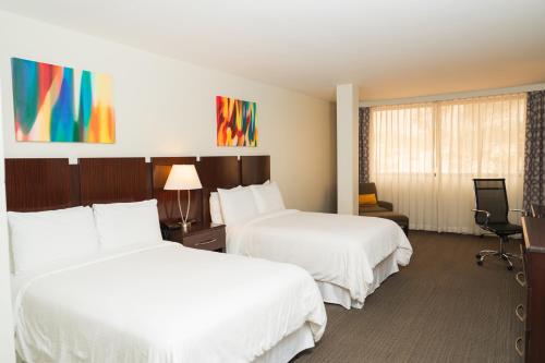 圣佩德罗苏拉Hotel Los Andes的有两张床和一把椅子的酒店房间