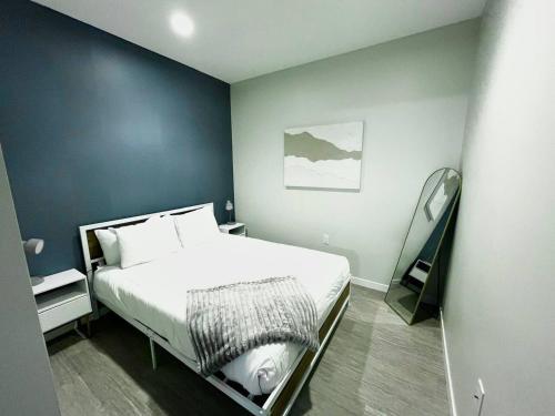 a bedroom with a white bed and a blue wall at Skyline Solace in Des Moines