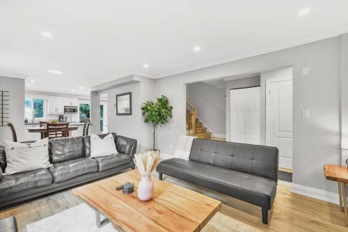 a living room with a black couch and a table at 3BR Pickering Retreat with BBQ and Patio Delight in Pickering