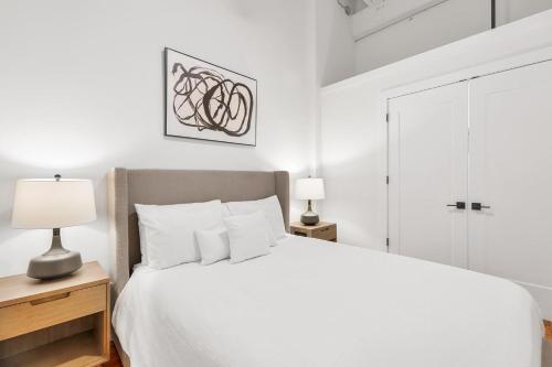 ein weißes Schlafzimmer mit einem weißen Bett und zwei Lampen in der Unterkunft Landing Apartments - Greenville in Greenville