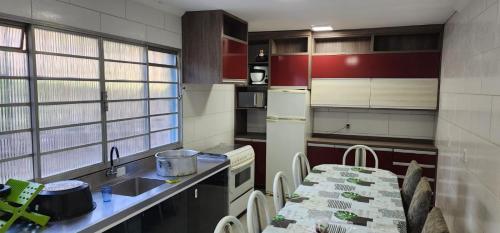 a kitchen with a table and a sink and a refrigerator at Chácara da família Santos in Itupeva