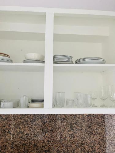 a white cabinet with plates and glasses on it at Lovely Seafront Apartment with Breathtaking Seaviews in Cupecoy
