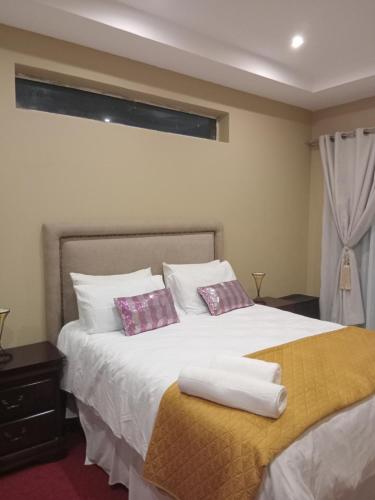 a bedroom with a bed with two pillows on it at Lovemoreheights Inn in Gqeberha