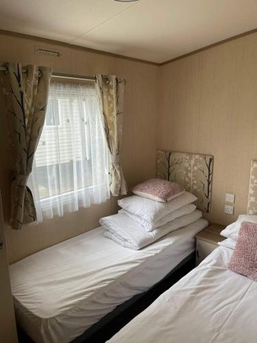 two beds in a small room with a window at Lovely 6 berth caravan Haven wild duck hoilday park in Belton