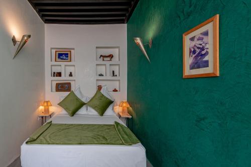 a bedroom with a green accent wall and a bed at Riad GUENAOUA Jacuzzi & Rooftop in Marrakesh