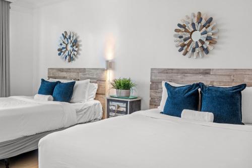 two beds in a bedroom with blue pillows at Condado Lagoon by Otium in San Juan
