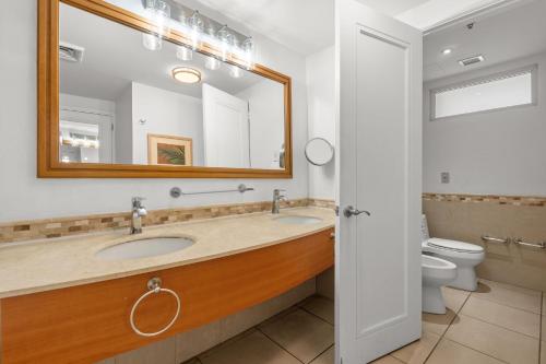 a bathroom with a sink and a mirror and a toilet at Condado Lagoon by Otium in San Juan