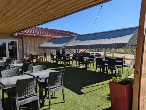 a patio with tables and chairs on the grass at Mobil home Apollon Riviera in Saint-Papoul