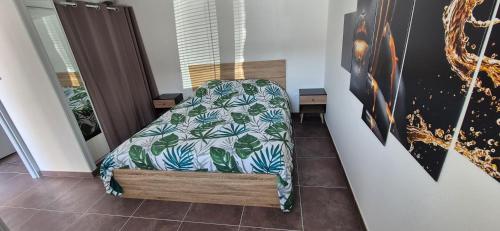 Schlafzimmer mit einem Bett mit einer grünen und weißen Bettdecke in der Unterkunft Maison plein coeur de village in Villevieux