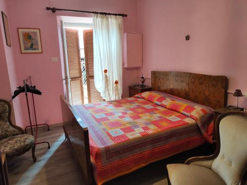 a bedroom with a bed and a chair and a window at Casa di Rosa in Cureggio