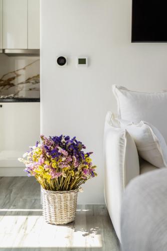 a bouquet of flowers in a basket next to a couch at Nefeli Residence & Suite Ftelia beach Mykonos in Elia
