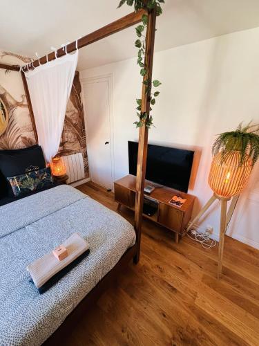 a bedroom with a bed and a table with a lamp at Studio Exotique Hyper-Centre Enghien 12min Paris in Enghien-les-Bains
