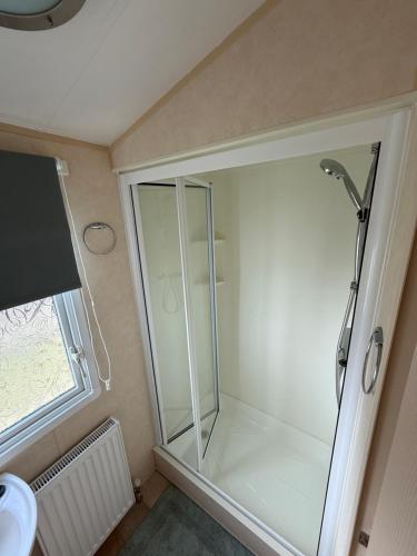 eine Glasdusche im Bad mit Fenster in der Unterkunft 8 Berth Caravan in Chapel St in Chapel Saint Leonards