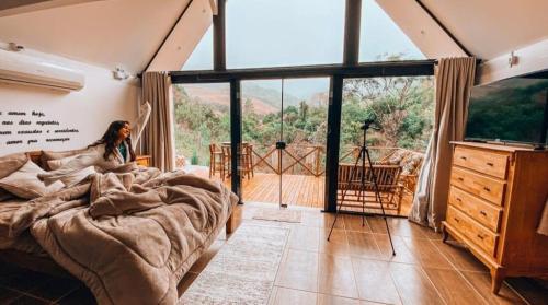 una donna in una camera da letto con un letto e una grande finestra di Recanto Bellavita - Rancho Queimado/SC a Rancho Queimado
