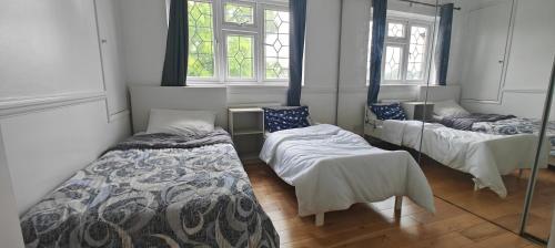 a room with three beds and two windows at Family house in Greenwich in Eltham