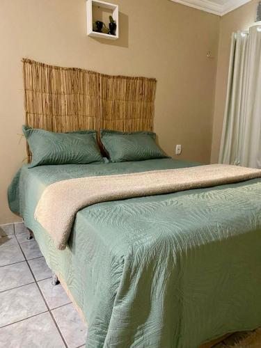 a bedroom with a green bed with a wooden headboard at Hostel Wei in Boa Vista